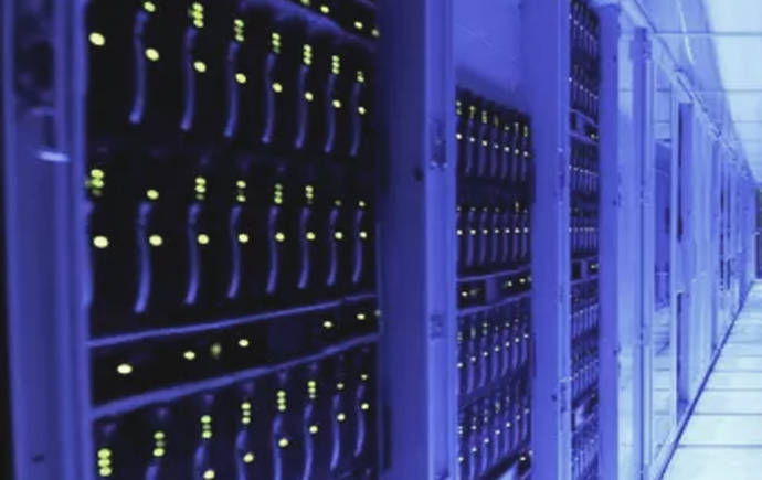 Rows of server racks receding down a data-centre aisle, status lights along every shelf